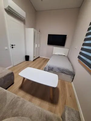 a small room with two beds and a white table at Kambarių nuoma prie Kauno oro uosto in Karmėlava