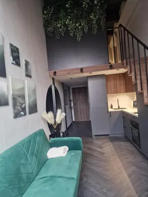 a living room with a green couch and a kitchen at Stylish loft in Vilnius