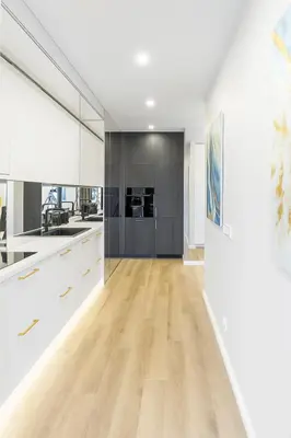 a kitchen with white cabinets and a hardwood floor at Self Check-in Apartment in Vilnius
