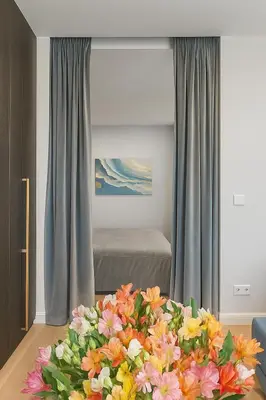 a room with a bed and a table with flowers at Self Check-in Apartment in Vilnius