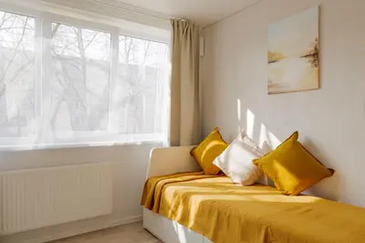 a bedroom with a bed with yellow sheets and a window at Vilnius prie centro ramybė tarp medžių in Vilnius