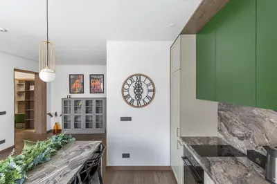 a kitchen with white walls and a clock on the wall at Kaunas old town apartment in Kaunas