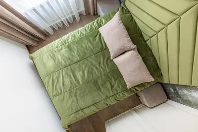 an overhead view of a bed with green sheets and pillows at Kaunas old town apartment in Kaunas
