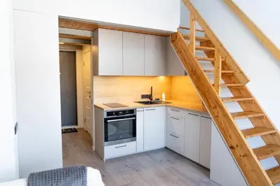 a kitchen with white cabinets and a wooden staircase at Loftas Dumu fabrikas in Vilnius