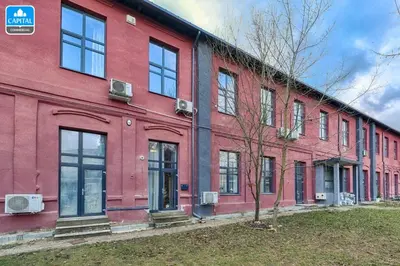 a red building with windows and a tree in front of it at Loftas Dumu fabrikas in Vilnius