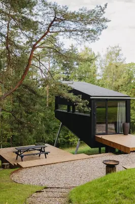 a black house with a picnic table and a bench at Blackview cabin in Kulautuva