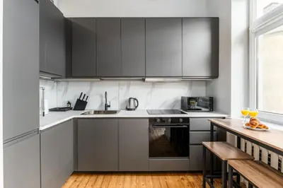 a kitchen with gray cabinets and a wooden floor at Charming Apartment in Kaunas Old Town in Kaunas