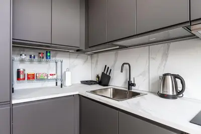 a kitchen with a stainless steel sink and white cabinets at Charming Apartment in Kaunas Old Town in Kaunas