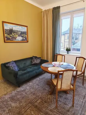 a living room with a green couch and a table at Cozy Fryko Era Home - 1929, 2 double beds in Kaunas