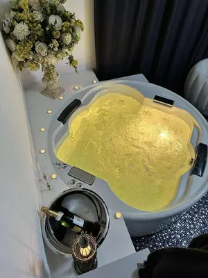 a bathroom sink with a bottle of champagne and a vase of flowers at Host 5 apartment in Kaunas