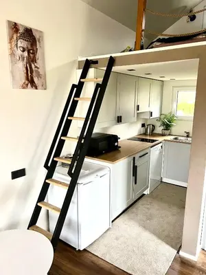 a kitchen with white cabinets and a spiral staircase at Pas Milėją