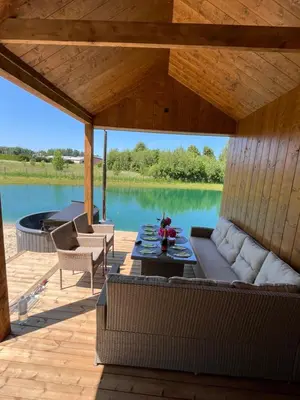 a patio with a couch and a table on a lake at Pas Milėją