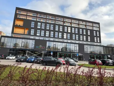 a large building with cars parked in a parking lot at EGo Apartment in Vilnius