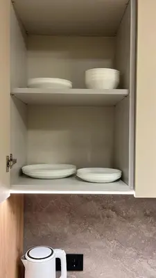 a cabinet filled with white plates and bowls at Laisves alejos Apartments in Kaunas