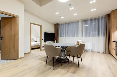 a dining room with a table and chairs and a bedroom at Laisves alejos Apartments in Kaunas