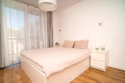 a white bedroom with a white bed and a window at NewTown Krėvos Apartments in Kaunas