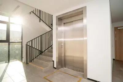 a hallway with a door and stairs with a window at NewTown Krėvos Apartments in Kaunas