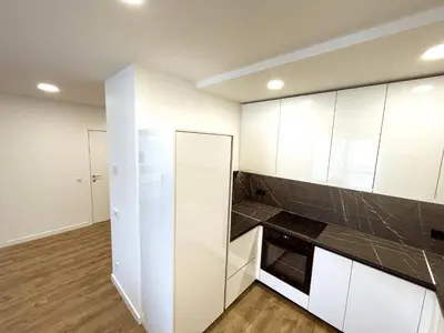 a kitchen with white cabinets and black counter tops at NewTown Krėvos Apartments in Kaunas