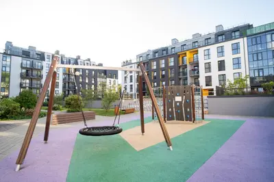 a playground with two swings and a tire at NewTown Krėvos Apartments in Kaunas