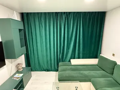 a living room with a green couch and a green curtain at Welcome to Dovas Home in Anykščiai