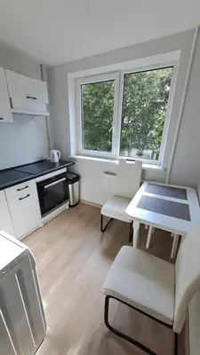 a kitchen with a table and two chairs and two windows at Irenos Nuoma in Šiauliai