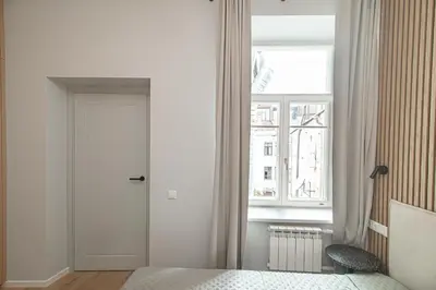 a white bedroom with a door and a window at Orbis Old Town Suites in Vilnius