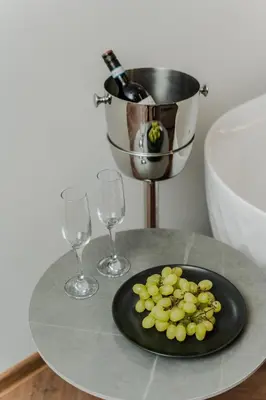 a plate of grapes on a table with two wine glasses at Chamber Luxury House in Kaunas