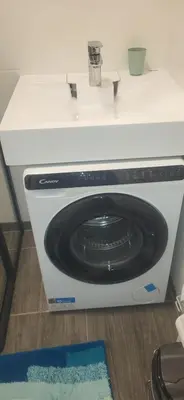 a washing machine sitting under a white counter at Vilniaus alėja 4 in Druskininkai