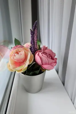 a white vase with flowers on a window sill at Apartamentai Šiaulių miesto centre in Šiauliai
