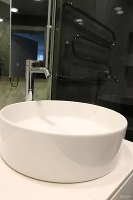 a white sink in a bathroom with a faucet at Apartamentai Šiaulių miesto centre in Šiauliai