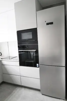 a white kitchen with a refrigerator and an oven at Apartamentai Šiaulių miesto centre in Šiauliai