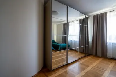 a room with a mirrored closet with a green chair at Julias's House in Šiauliai