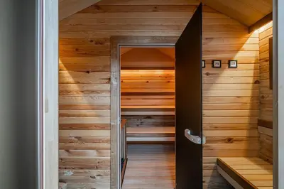 a sauna with wood paneling and a glass door at Private Lake Escape- 6BR, Sauna & Bonfire in Skersabaliai