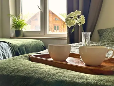 a tray with two cups and a vase with flowers on a bed at Private Lake Escape- 6BR, Sauna & Bonfire in Skersabaliai