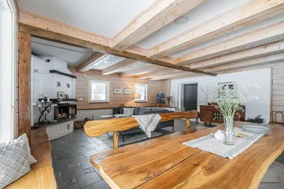 a living room with wooden ceilings and a table at Private Lake Escape- 6BR, Sauna & Bonfire in Skersabaliai