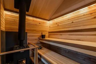 a wooden sauna with a fireplace in it at Private Lake Escape- 6BR, Sauna & Bonfire in Skersabaliai