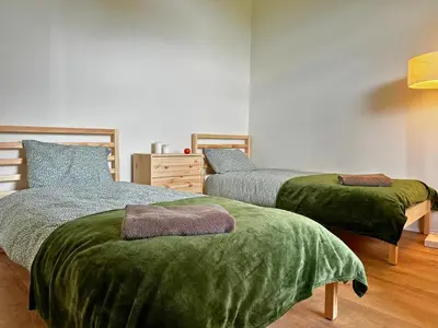a bedroom with two beds with green blankets at Private Lake Escape- 6BR, Sauna & Bonfire in Skersabaliai
