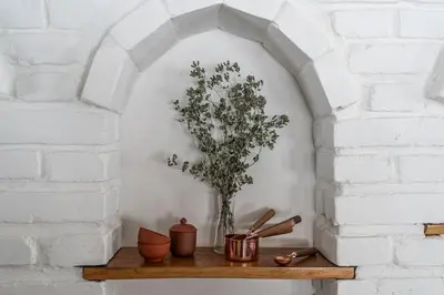 a white brick wall with a shelf with a plant on it at Private Lake Escape- 6BR, Sauna & Bonfire in Skersabaliai