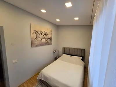 a bedroom with a bed and a painting on the wall at Jaukus butas Panemunėje su vaizdu į Nemuną in Kaunas