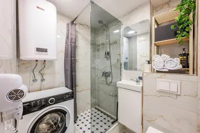 a washing machine in a bathroom with a shower at Cozy airport apartment