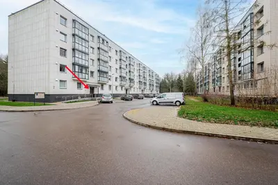 a street with cars parked in front of a building at Cozy airport apartment