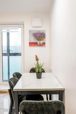 a white table and chairs in a room with a window at Cozy airport apartment