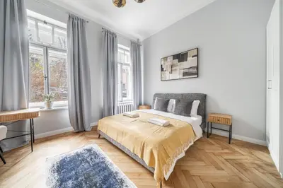 a white bedroom with a bed and two windows at Newly Refurbished Luxurious 2 Bedroom Apartment by Reside Baltic in Vilnius