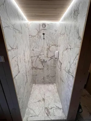 a bathroom with a walk in shower with marble tiles at Pas Rimute in Zapyškis