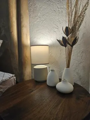 three white vases on a wooden table with a lamp at Urban oasis apartments in Vilnius