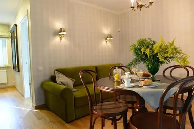 a living room with a table and a green couch at Vila Klasika in Birštonas
