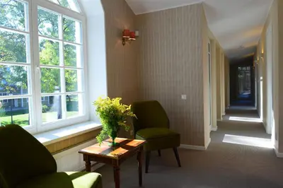 a hallway with two chairs and a table and windows at Vila Klasika in Birštonas