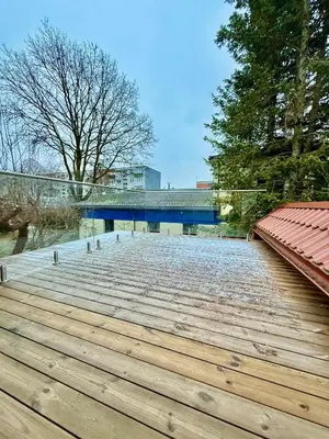 a large wooden deck with a bridge in the background at Centro apartamentai in Radviliškis