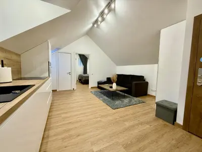 a kitchen and living room with white walls and wood floors at Centro apartamentai in Radviliškis