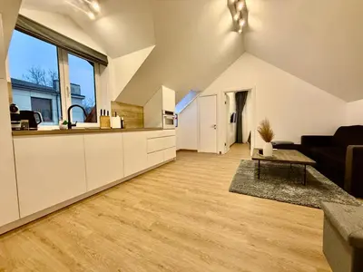 an attic kitchen and living room with white cabinets at Centro apartamentai in Radviliškis